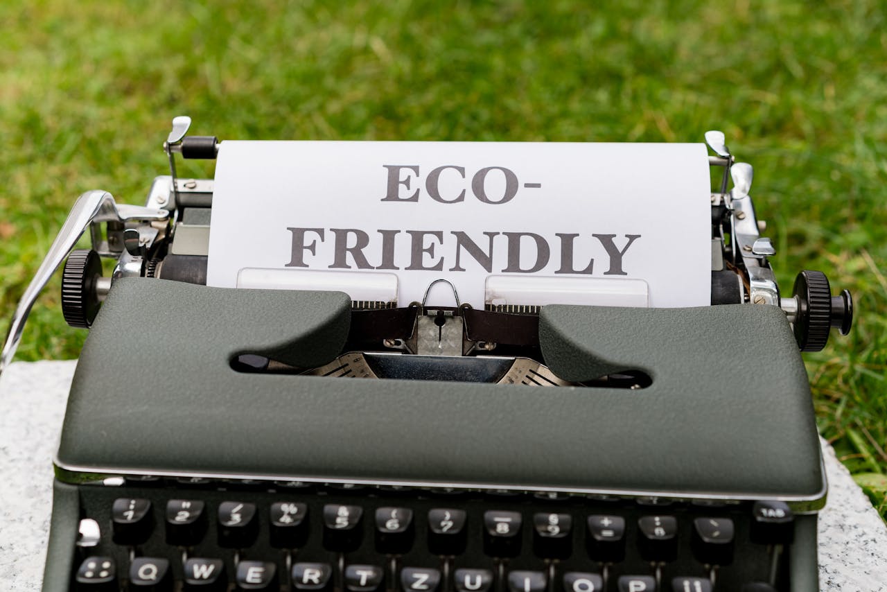A vintage typewriter displays an eco-friendly message outdoors on grass.