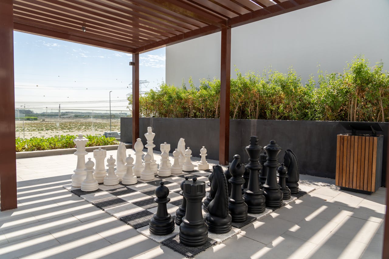 Large outdoor chess set under a pergola in Dubai, UAE, offering shade and leisure.